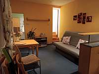 Obývací pokoj s rozkládací pohovkou, stolem a kuchyňským koutem., - apartmán k pronájmu Teplice nad Metují